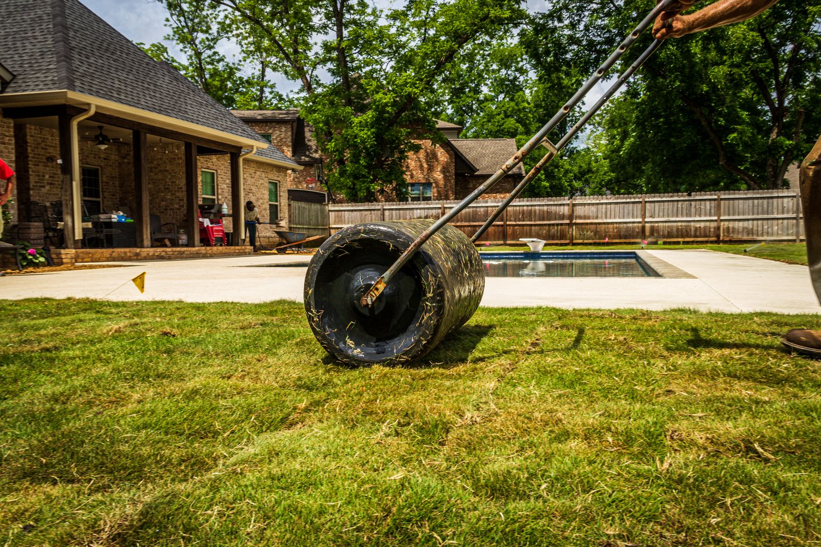 Weighted lawn roller pressing newly laid sod into firm contact with the soil
