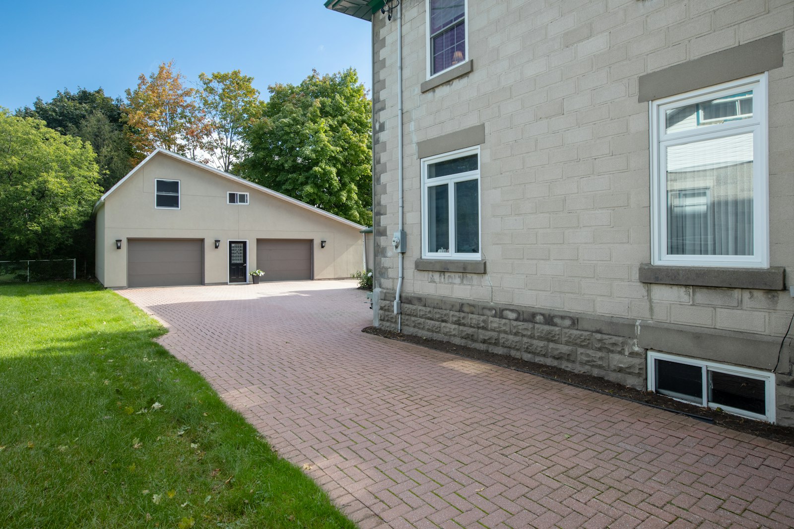 Paver driveway leading to an attached garage alongside a two-story home