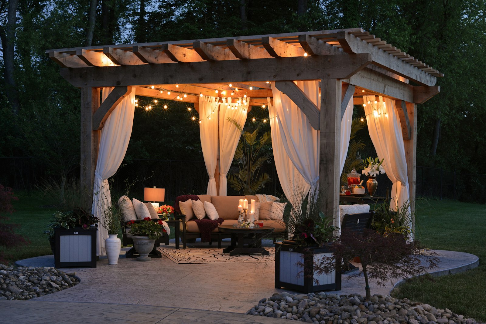 Wood pergola with string lights, curtains and outdoor seating over a patio